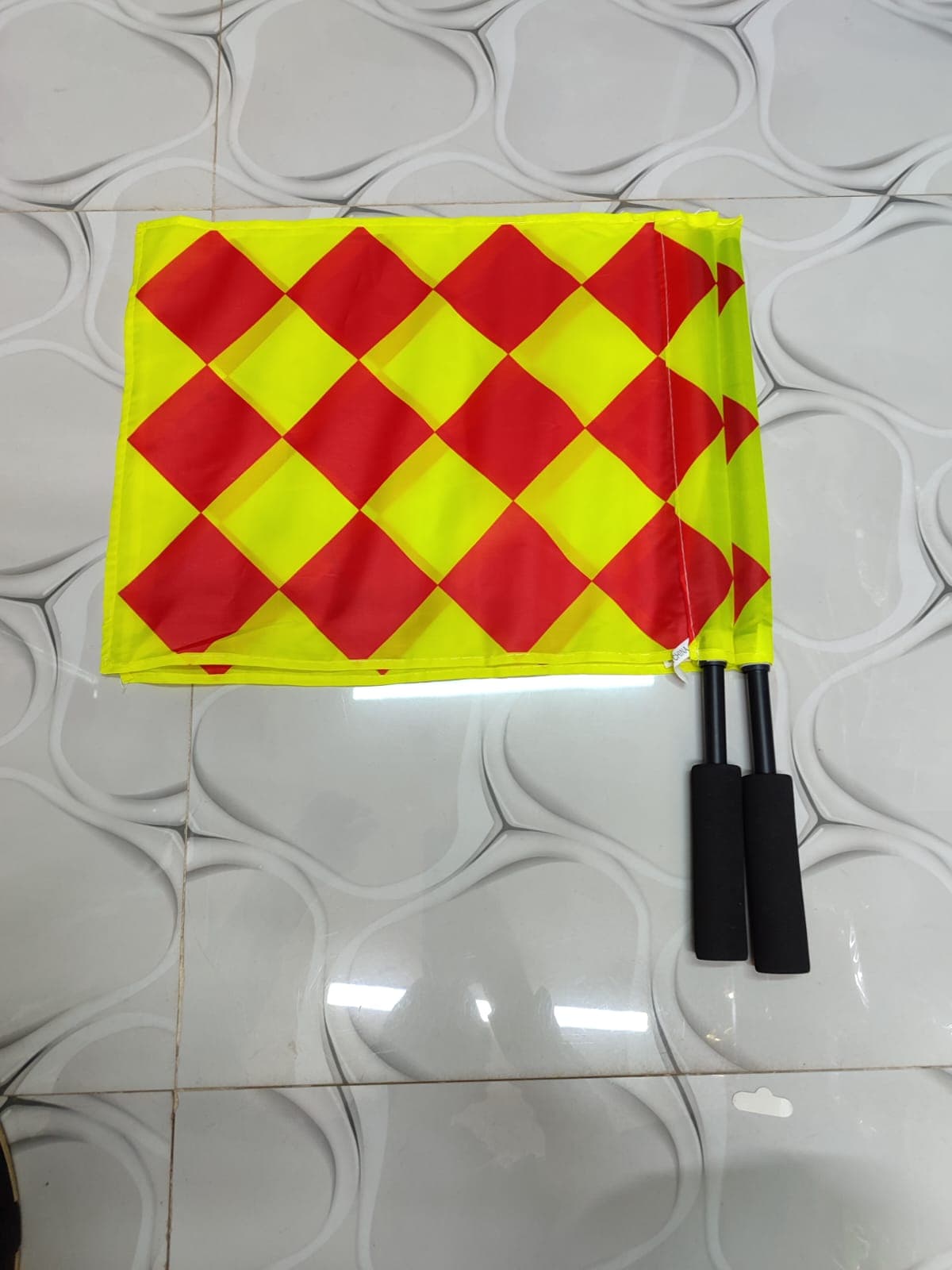A pair of assistant referee flags designed for football match officials. The flags feature a highly visible fluorescent yellow and red checkered pattern, making them easy to see from a distance.